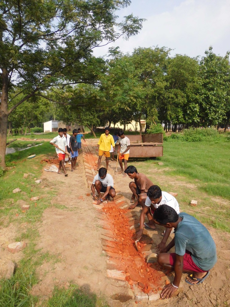 Senior boys constructing shallow drains for diverting the rain water